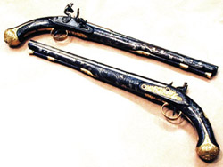 Pair of long flintlock pistols, c.1800 with gilt mounts and silver decoration to the stocks